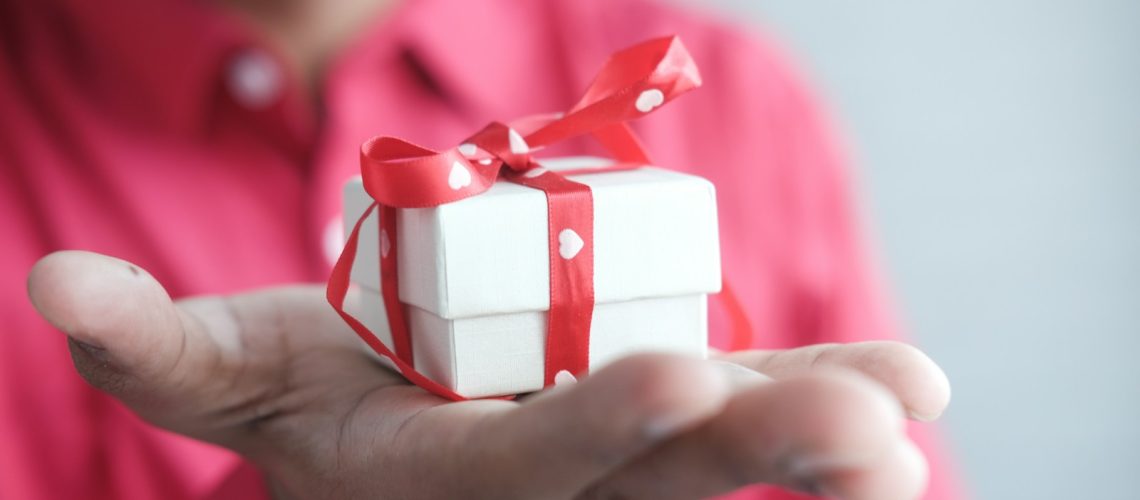 gift for man Best Retirement Gifts for Men a man holding a white gift box with a red ribbon Best Retirement Gifts for Men