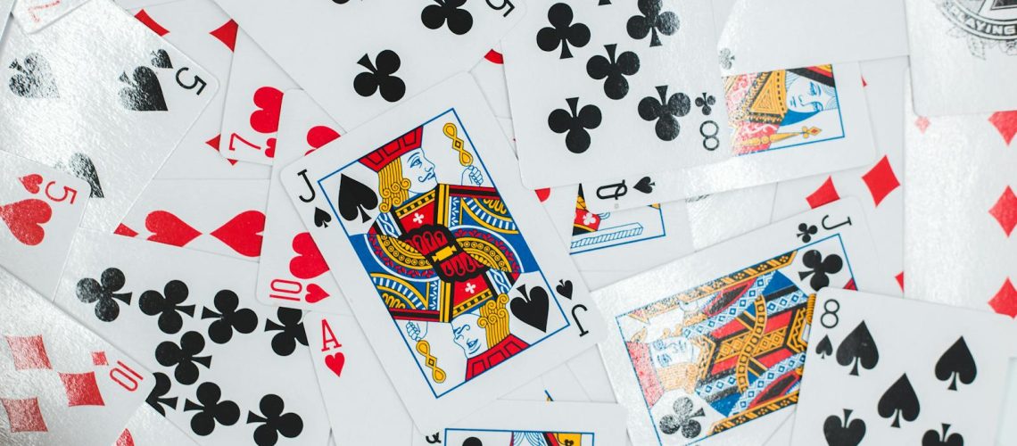 Solitaire Card Game Photo by Erik Mclean Colorful assortment of playing cards laid out in a chaotic pattern, showcasing various suits and face cards.